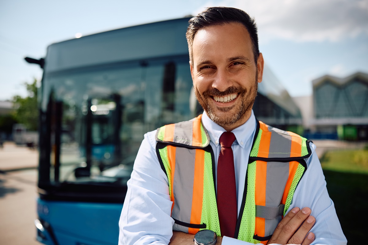 Happy city bus driver at the station looking at camera.